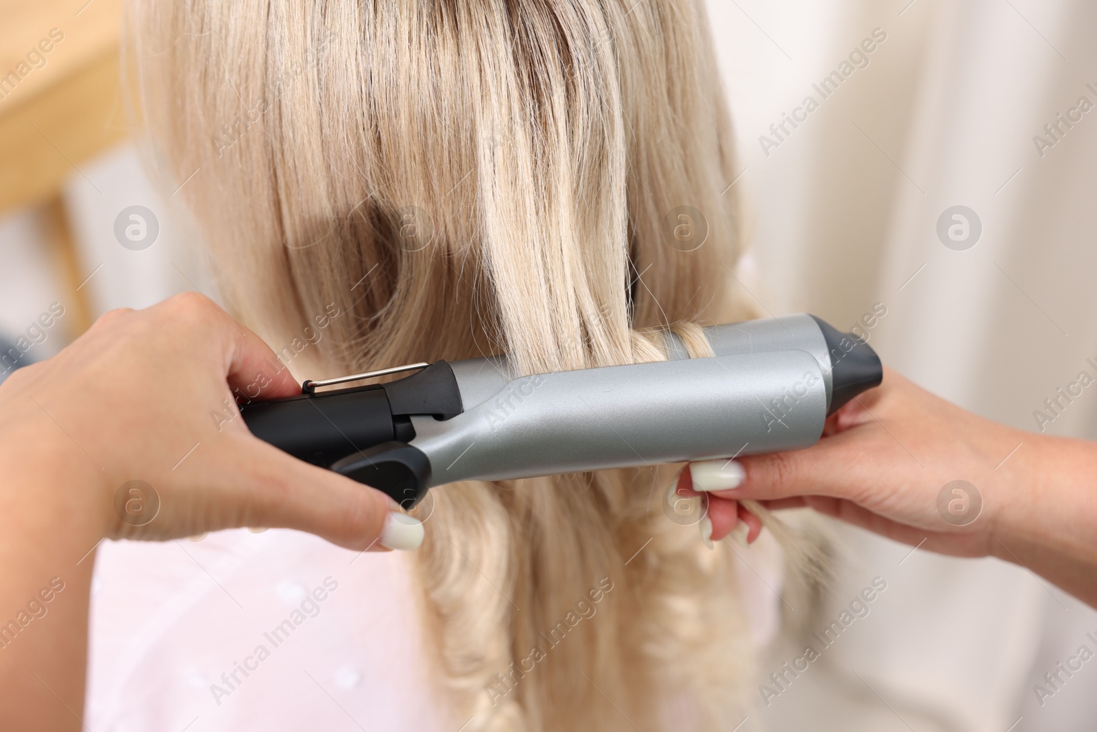 Hairdresser curling woman's hair in salon, closeup Photo of Hairdresser curling woman's hair in salon, closeup