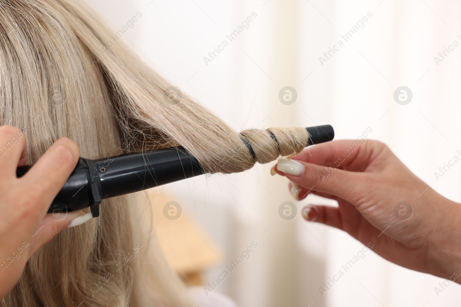 Hairdresser curling woman's hair in salon, closeup Photo of Hairdresser curling woman's hair in salon, closeup