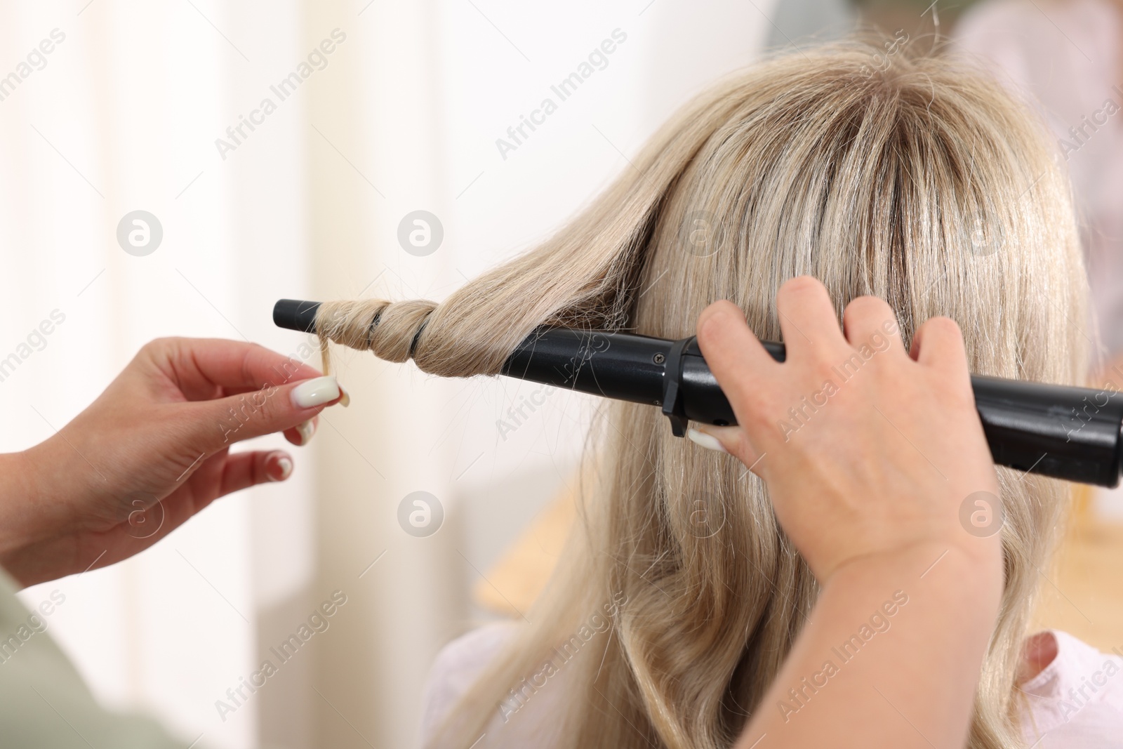 Hairdresser curling woman's hair in salon, closeup Photo of Hairdresser curling woman's hair in salon, closeup
