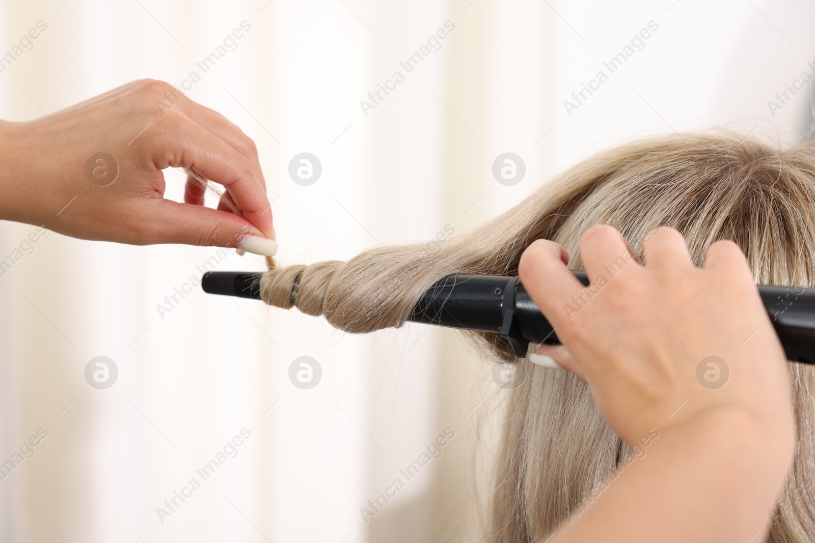 Hairdresser curling woman's hair in salon, closeup Photo of Hairdresser curling woman's hair in salon, closeup
