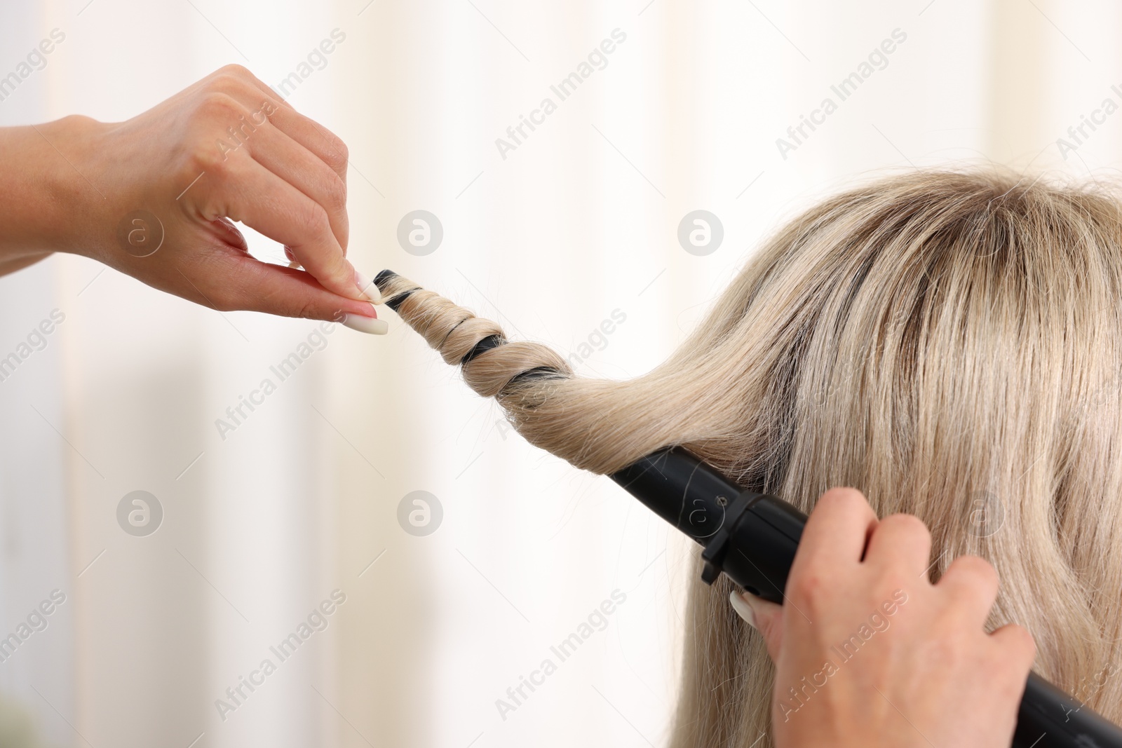 Hairdresser curling woman's hair in salon, closeup Photo of Hairdresser curling woman's hair in salon, closeup