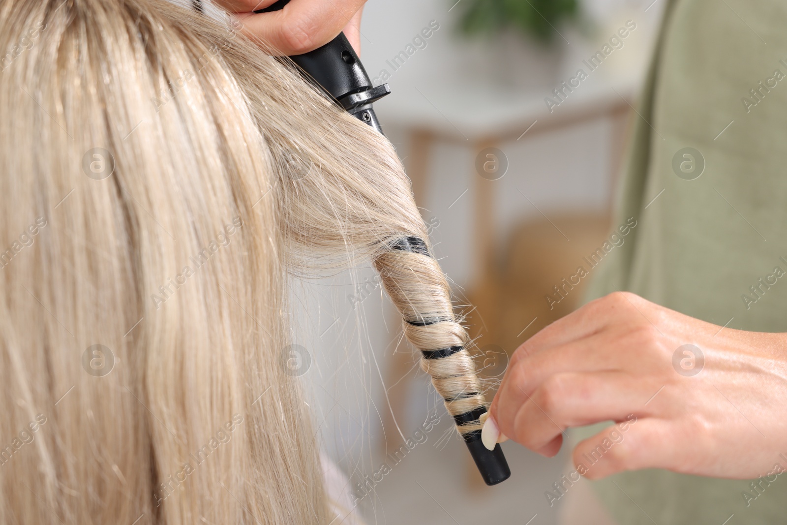 Hairdresser curling woman's hair in salon, closeup Photo of Hairdresser curling woman's hair in salon, closeup