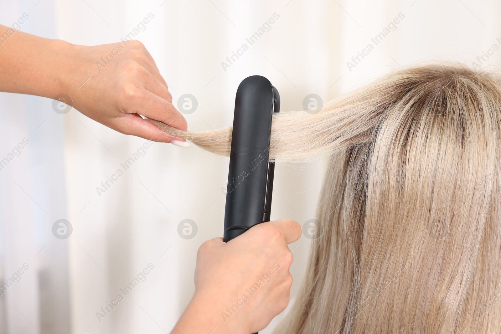 Hairdresser straightening woman's hair with flat iron in salon, closeup Photo of Hairdresser straightening woman's hair with flat iron in salon, closeup