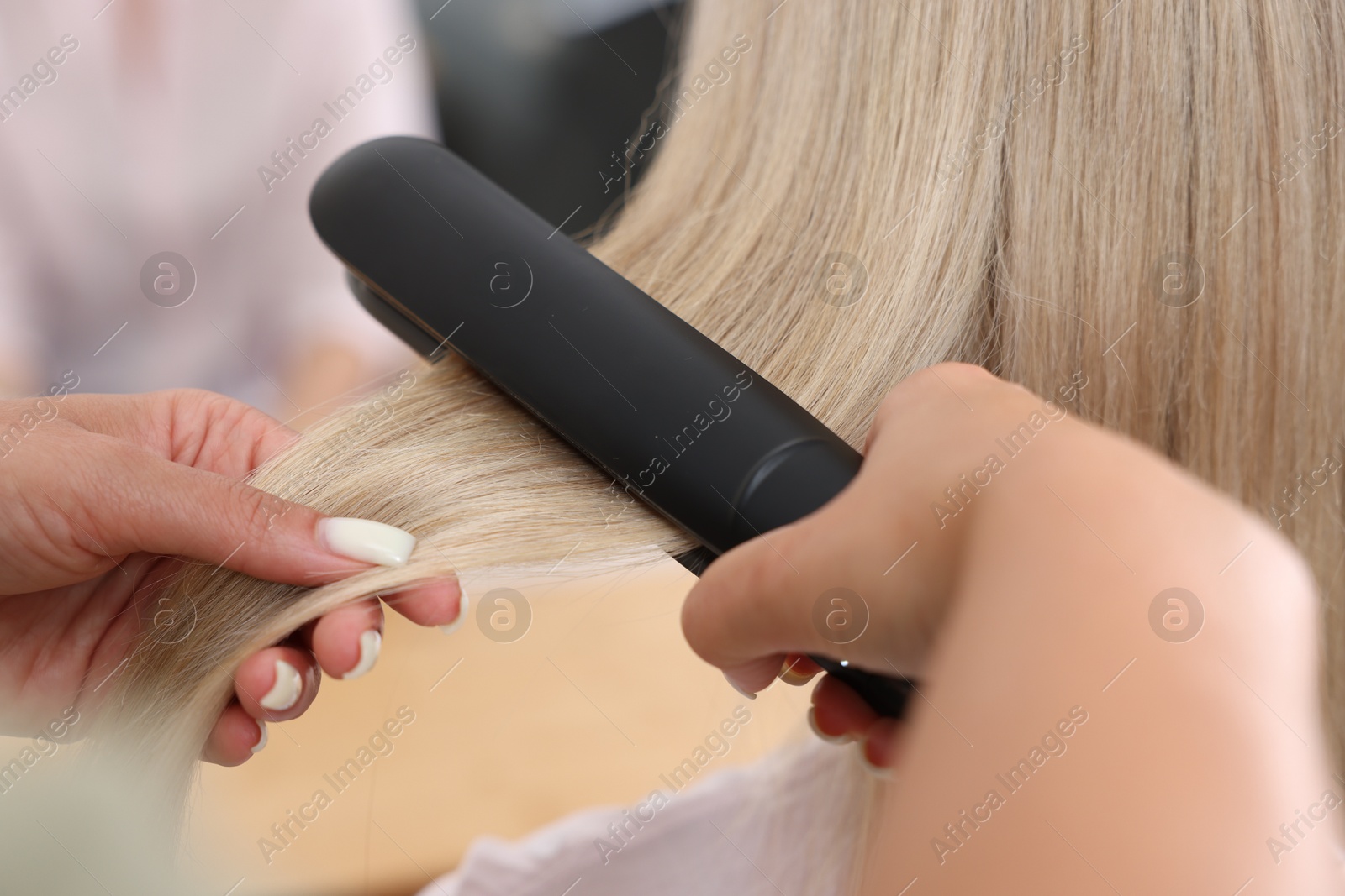 Hairdresser straightening woman's hair with flat iron in salon, closeup Photo of Hairdresser straightening woman's hair with flat iron in salon, closeup