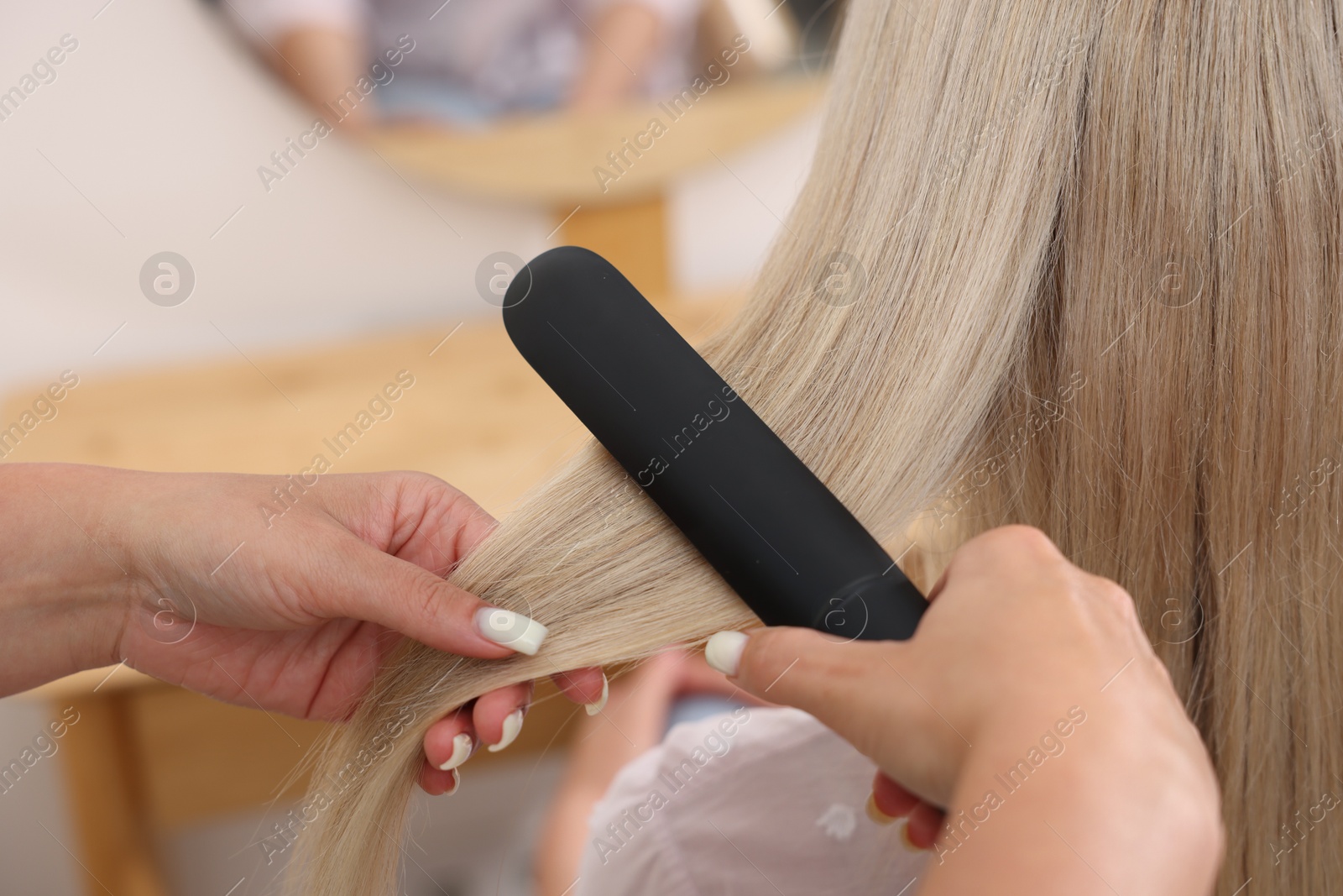 Hairdresser straightening woman's hair with flat iron in salon, closeup Photo of Hairdresser straightening woman's hair with flat iron in salon, closeup