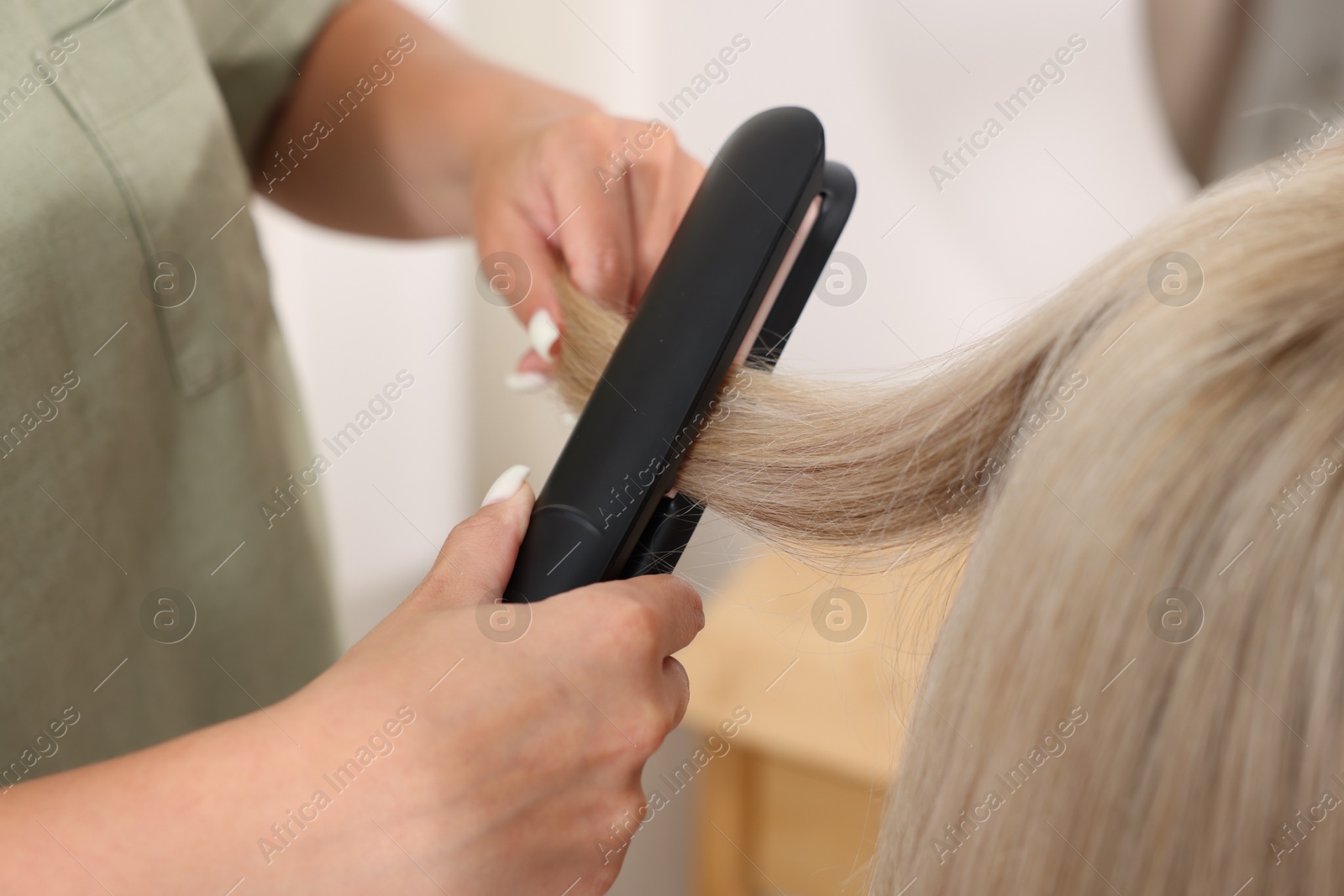 Hairdresser straightening woman's hair with flat iron in salon, closeup Photo of Hairdresser straightening woman's hair with flat iron in salon, closeup