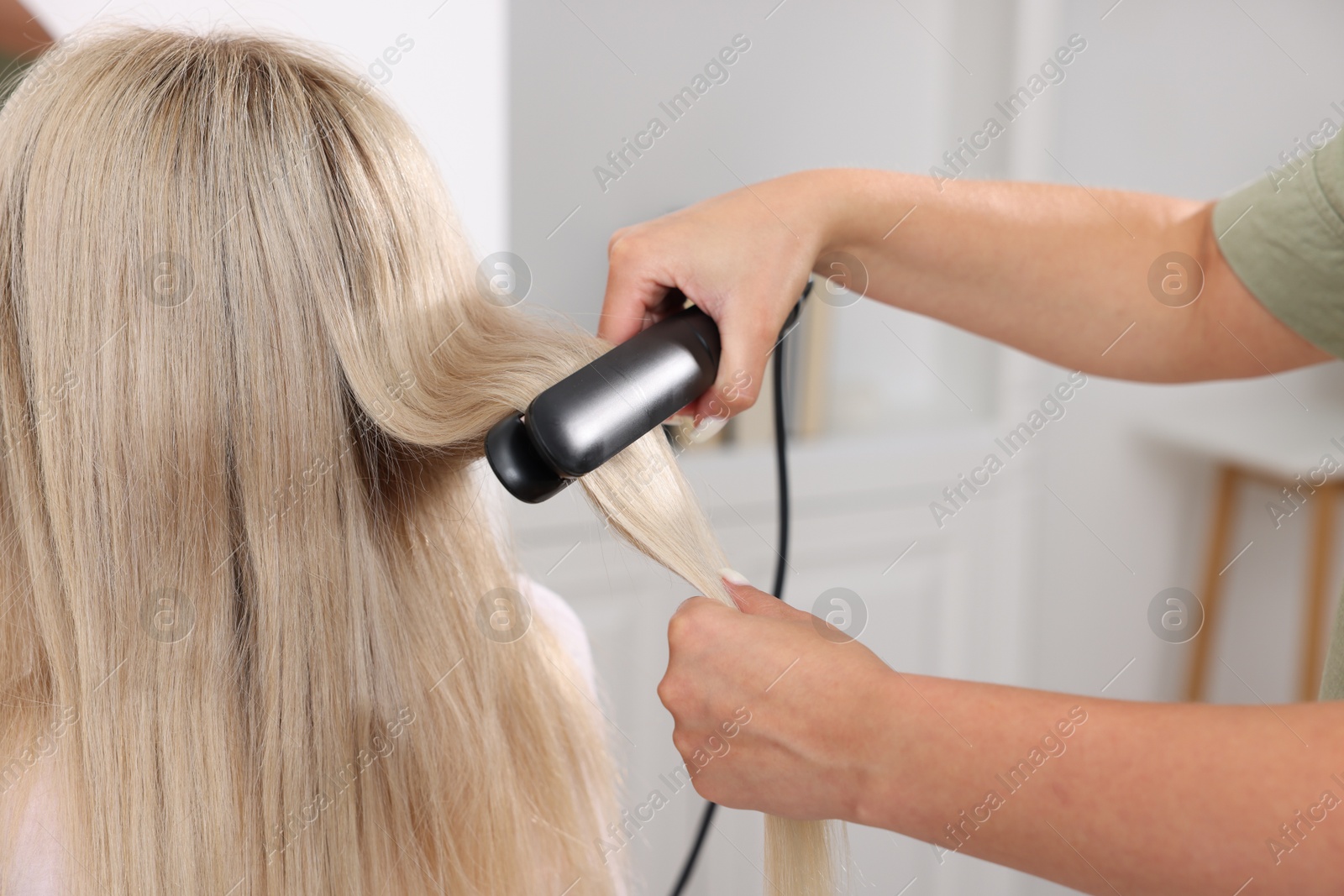 Hairdresser straightening woman's hair with flat iron in salon, closeup Photo of Hairdresser straightening woman's hair with flat iron in salon, closeup