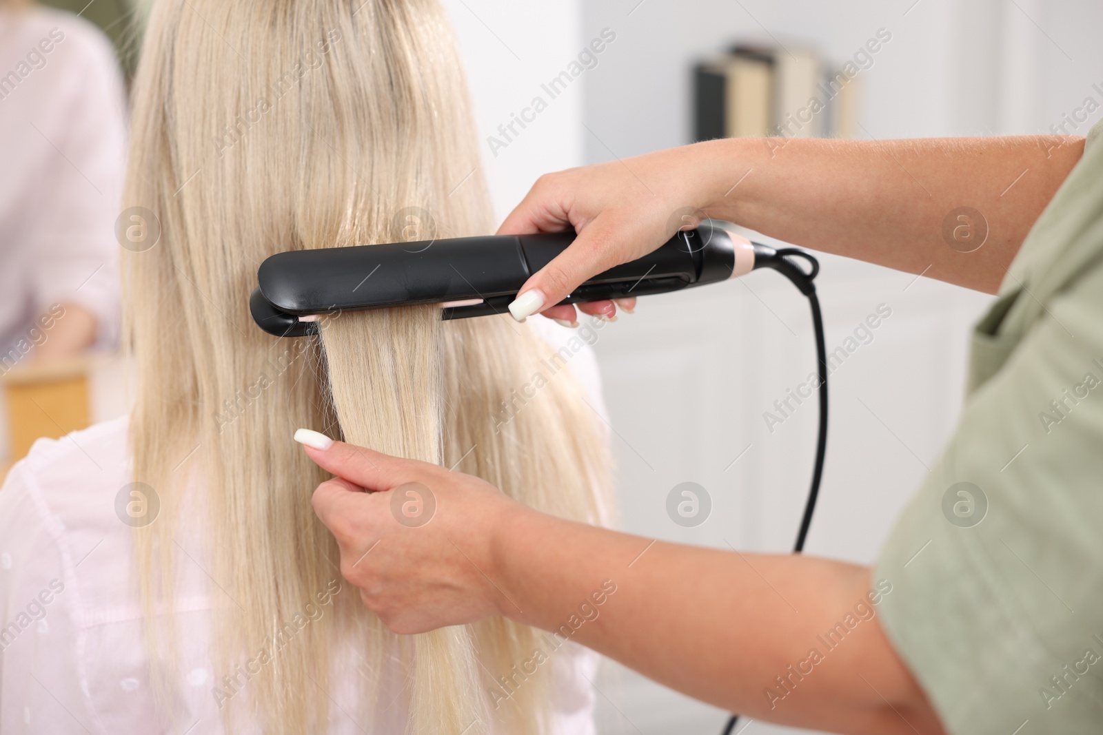 Hairdresser straightening woman's hair with flat iron in salon, closeup Photo of Hairdresser straightening woman's hair with flat iron in salon, closeup