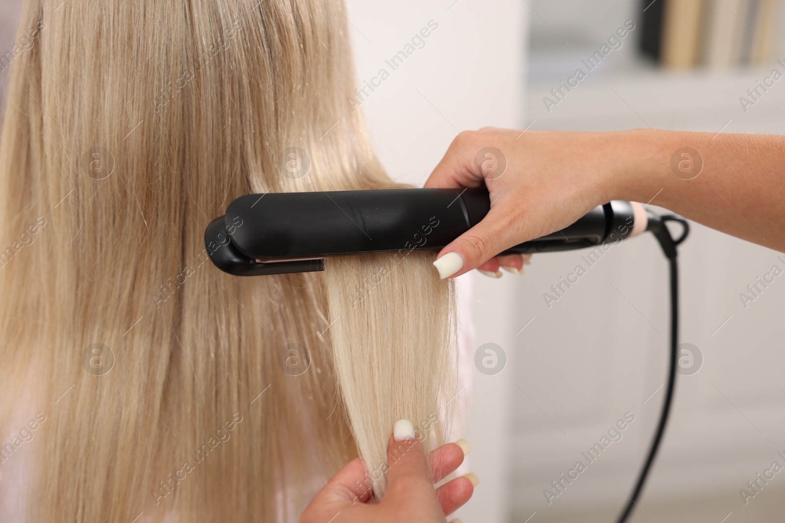 Hairdresser straightening woman's hair with flat iron in salon, closeup Photo of Hairdresser straightening woman's hair with flat iron in salon, closeup