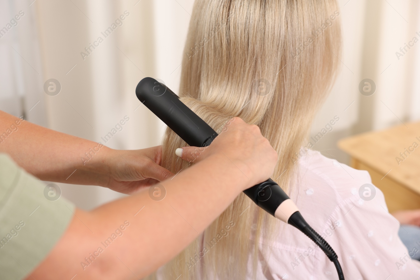 Hairdresser straightening woman's hair with flat iron in salon, closeup Photo of Hairdresser straightening woman's hair with flat iron in salon, closeup