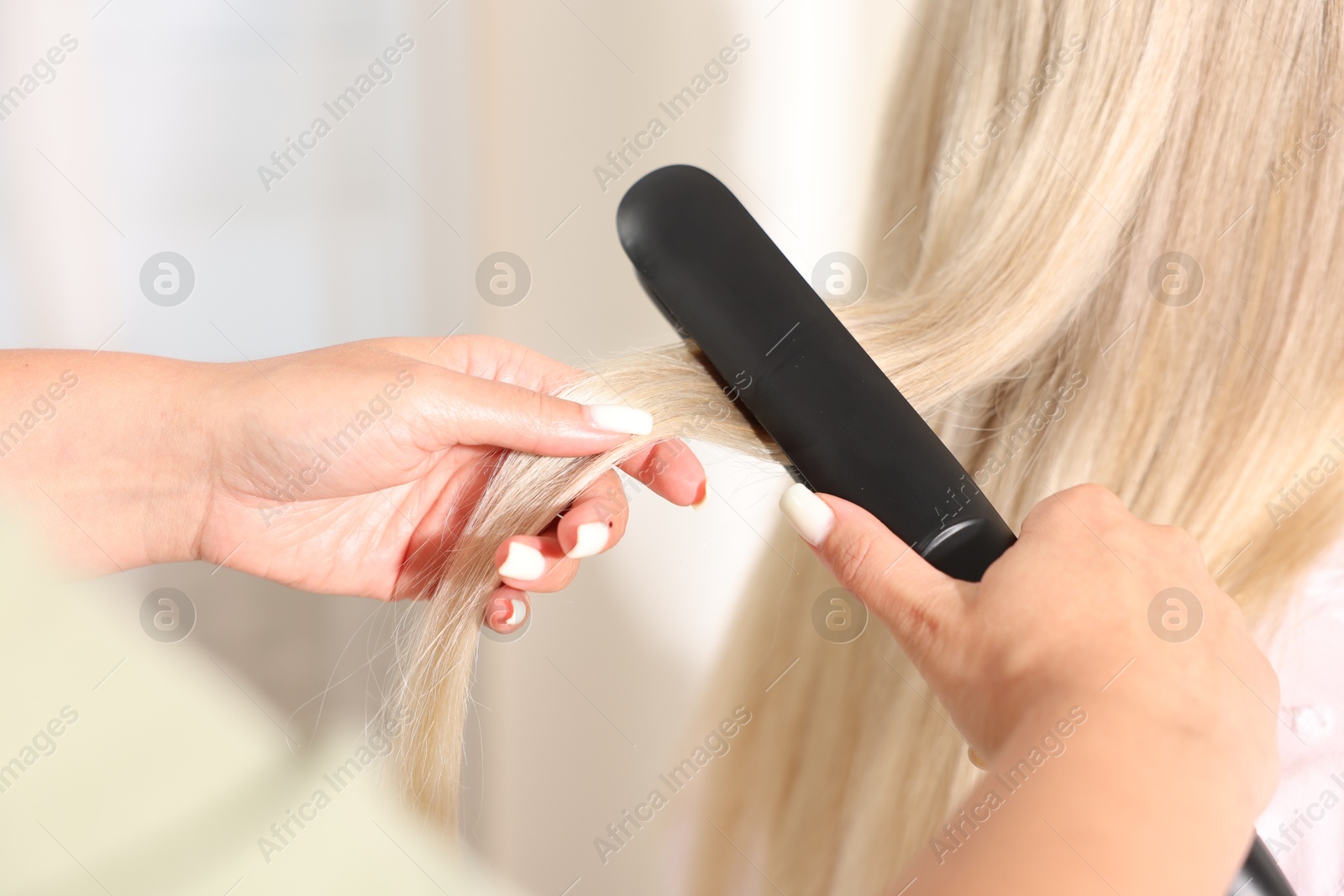 Hairdresser straightening woman's hair with flat iron in salon, closeup Photo of Hairdresser straightening woman's hair with flat iron in salon, closeup