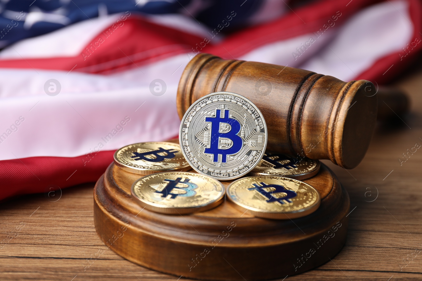 Cryptocurrency. Bitcoins, judge's gavel and American flag on wooden table, closeup Photo of Cryptocurrency. Bitcoins, judge's gavel and American flag on wooden table, closeup