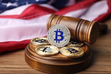 Photo of Cryptocurrency. Bitcoins, judge's gavel and American flag on wooden table, closeup