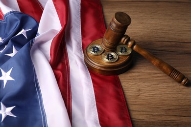 Photo of Cryptocurrency. Bitcoins, judge's gavel and American flag on wooden table, closeup