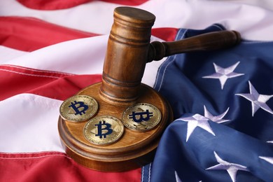 Photo of Cryptocurrency. Bitcoins and judge's gavel on American flag, closeup