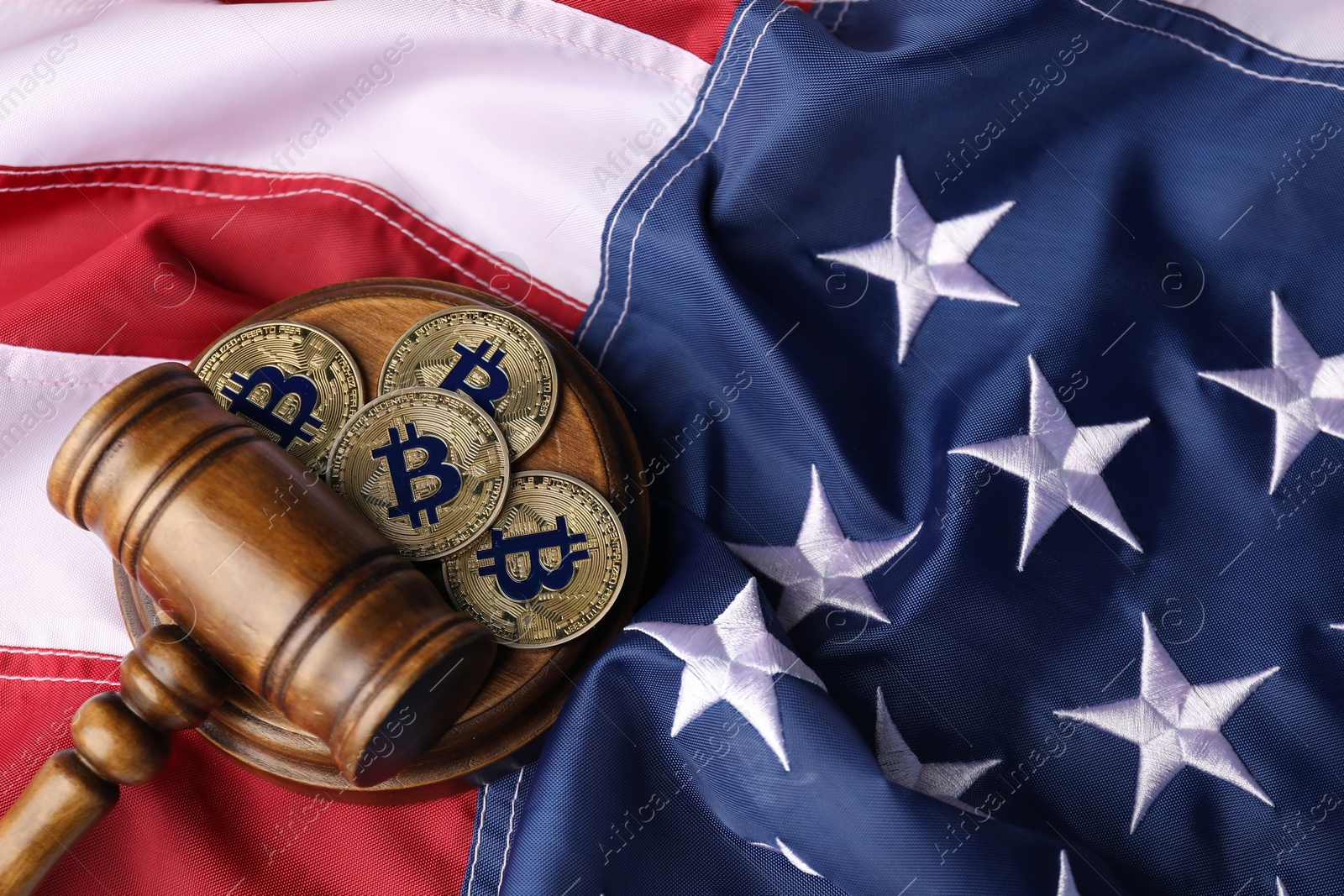 Photo of Cryptocurrency. Bitcoins and judge's gavel on American flag, above view. Space for text