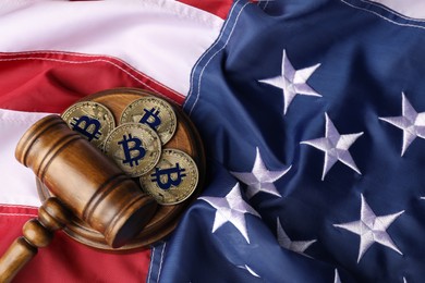 Photo of Cryptocurrency. Bitcoins and judge's gavel on American flag, above view. Space for text