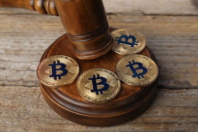 Photo of Cryptocurrency. Bitcoins and judge's gavel on wooden table, closeup