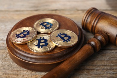 Photo of Cryptocurrency. Bitcoins and judge's gavel on wooden table, closeup