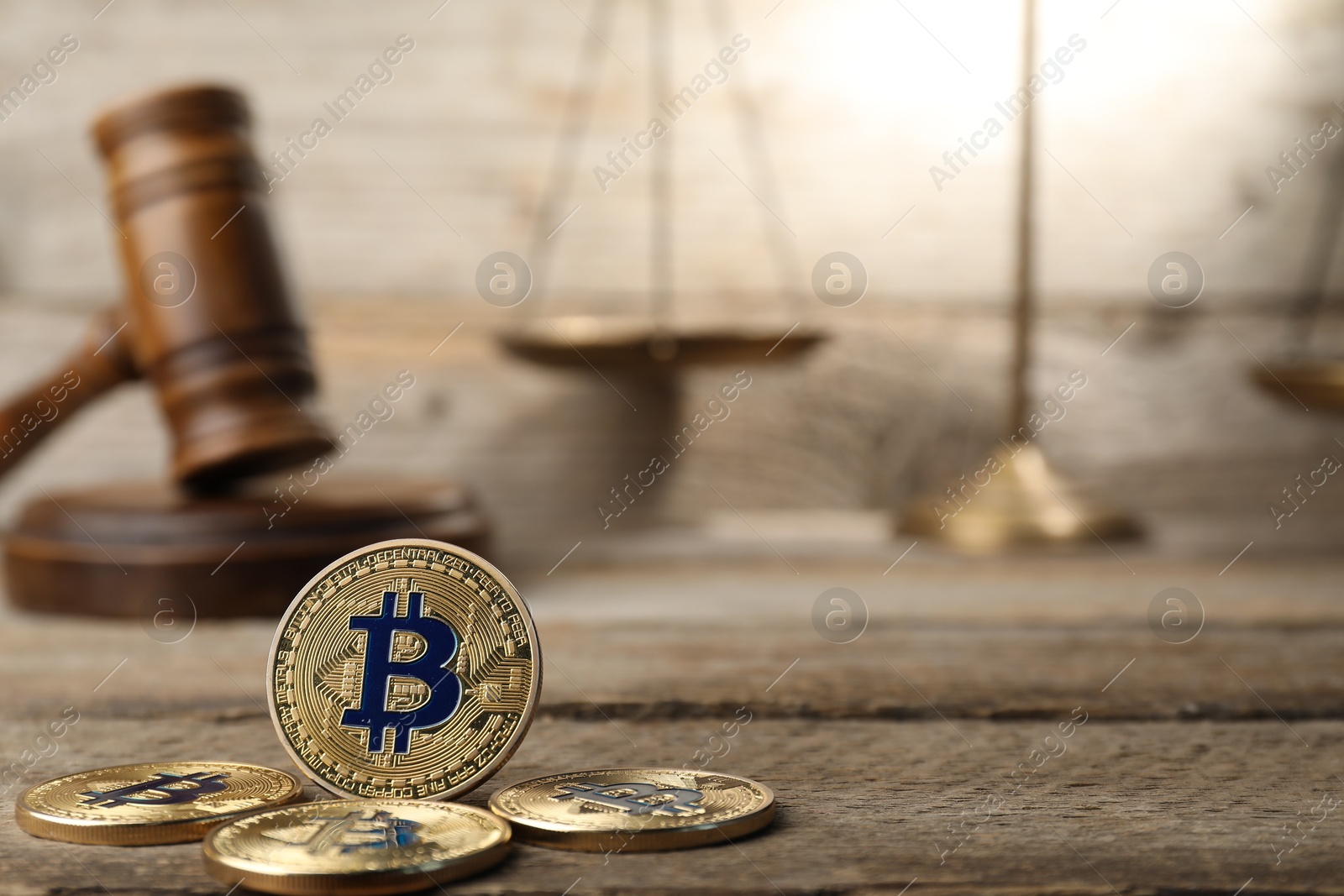 Photo of Cryptocurrency. Bitcoins, judge's gavel and scales on wooden table, closeup. Space for text