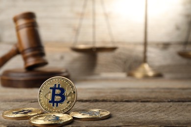 Photo of Cryptocurrency. Bitcoins, judge's gavel and scales on wooden table, closeup. Space for text
