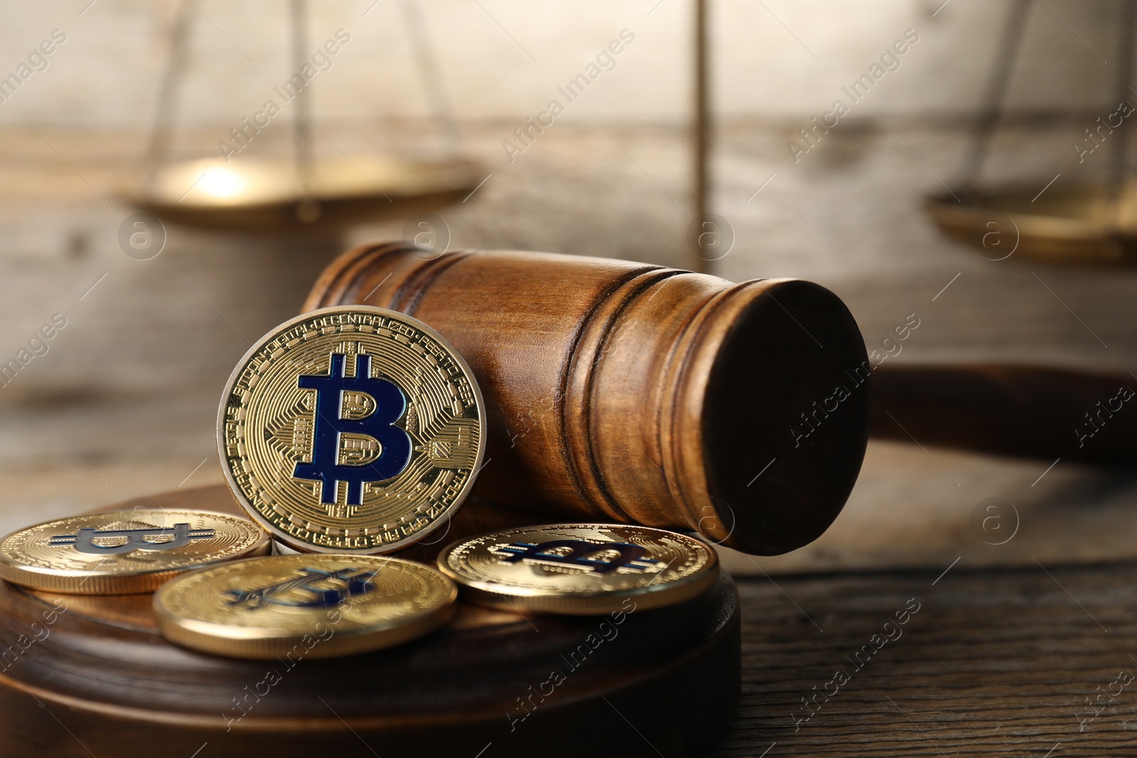 Cryptocurrency. Bitcoins, judge's gavel and scales on wooden table, closeup Photo of Cryptocurrency. Bitcoins, judge's gavel and scales on wooden table, closeup