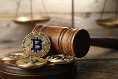 Photo of Cryptocurrency. Bitcoins, judge's gavel and scales on wooden table, closeup