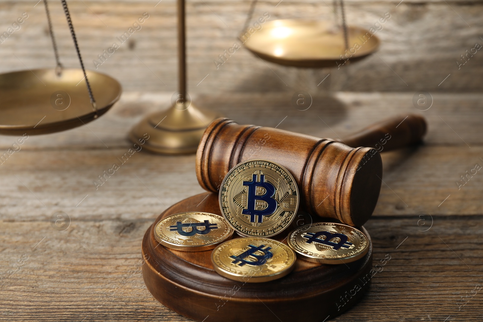 Cryptocurrency. Bitcoins, judge's gavel and scales on wooden table, closeup Photo of Cryptocurrency. Bitcoins, judge's gavel and scales on wooden table, closeup