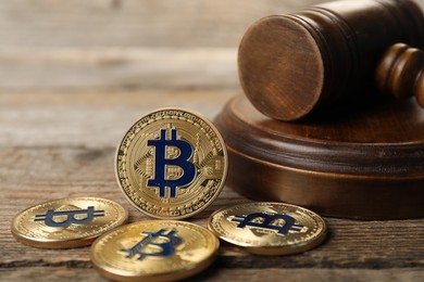 Photo of Cryptocurrency. Bitcoins and judge's gavel on wooden table, closeup