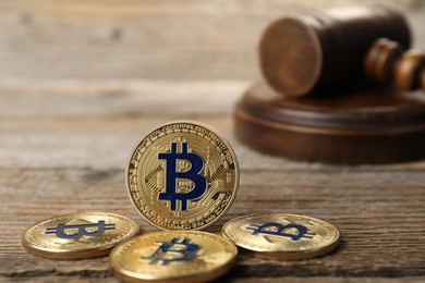 Photo of Cryptocurrency. Bitcoins and judge's gavel on wooden table, closeup