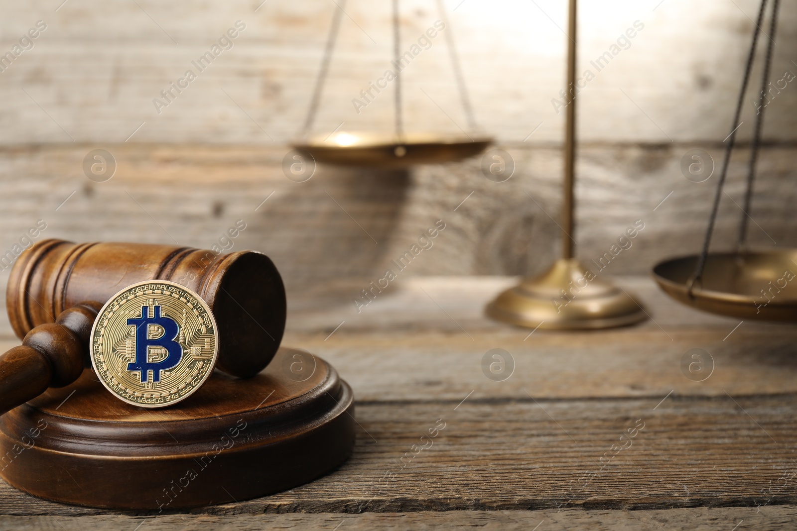 Photo of Cryptocurrency. Bitcoins, judge's gavel and scales on wooden table, closeup