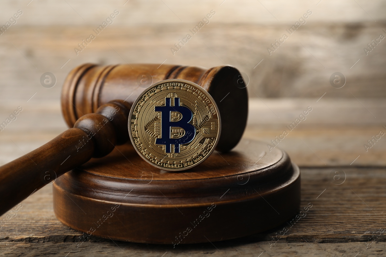 Photo of Cryptocurrency. Bitcoin and judge's gavel on wooden table, closeup