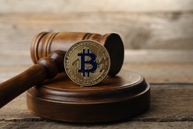 Photo of Cryptocurrency. Bitcoin and judge's gavel on wooden table, closeup