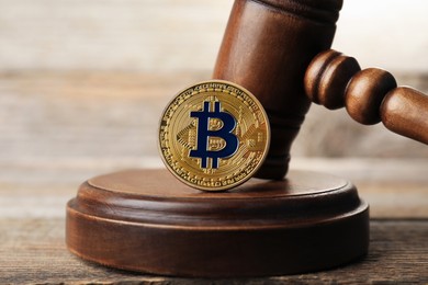 Photo of Cryptocurrency. Bitcoin and judge's gavel on wooden table, closeup