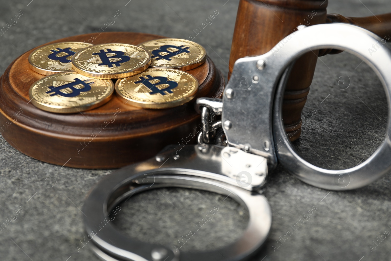 Cryptocurrency. Bitcoins, judge's gavel and handcuffs on grey table, closeup Photo of Cryptocurrency. Bitcoins, judge's gavel and handcuffs on grey table, closeup