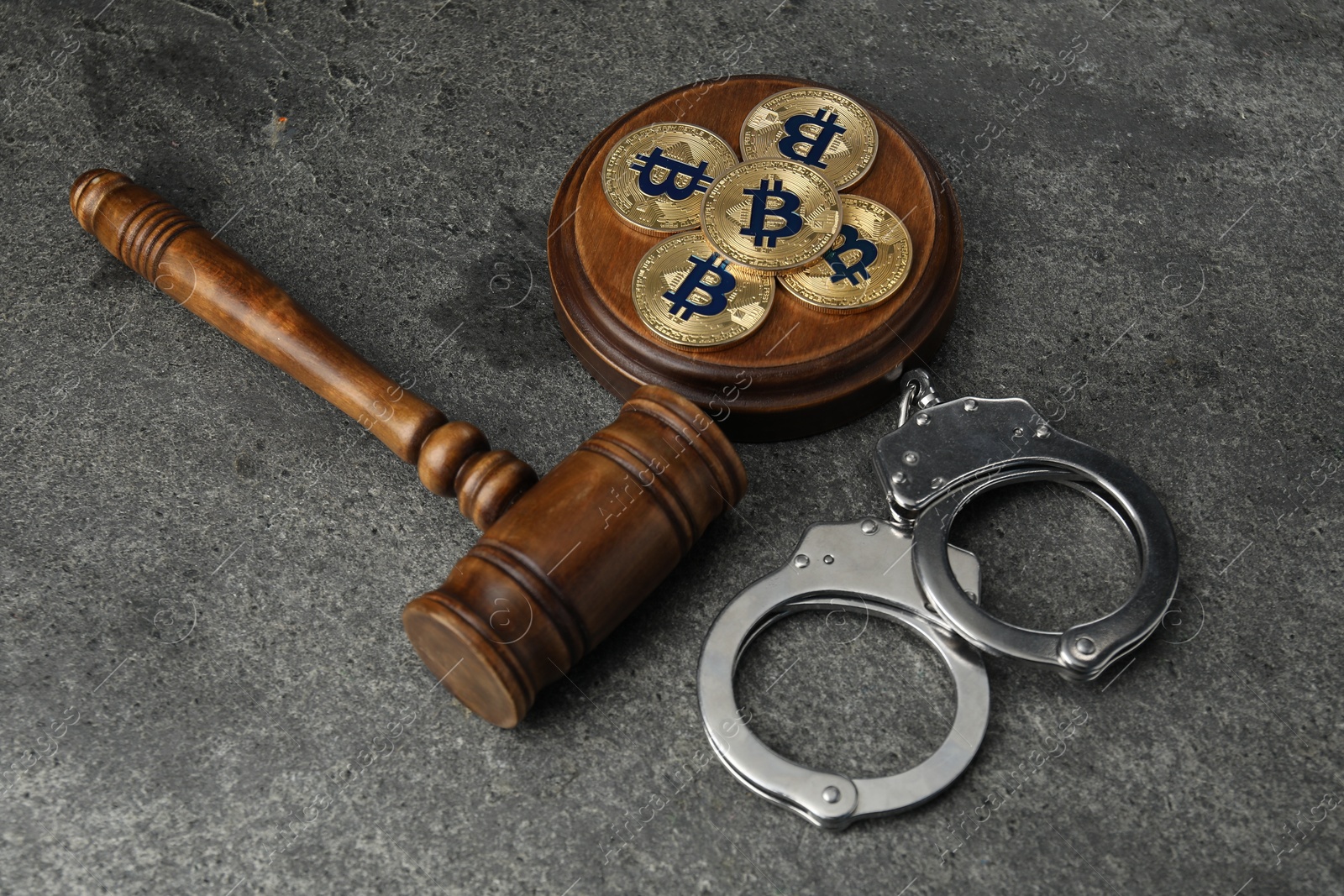 Photo of Cryptocurrency. Bitcoins, judge's gavel and handcuffs on grey table, above view