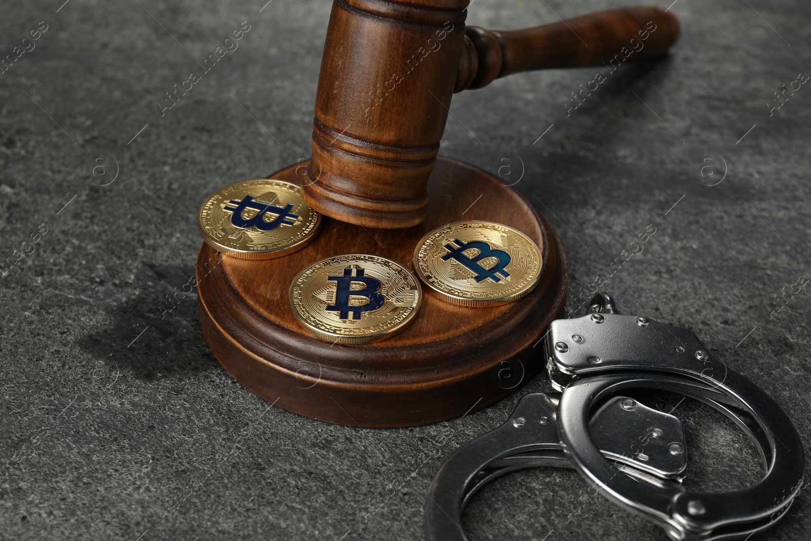 Cryptocurrency. Bitcoins, judge's gavel and handcuffs on grey table, closeup Photo of Cryptocurrency. Bitcoins, judge's gavel and handcuffs on grey table, closeup