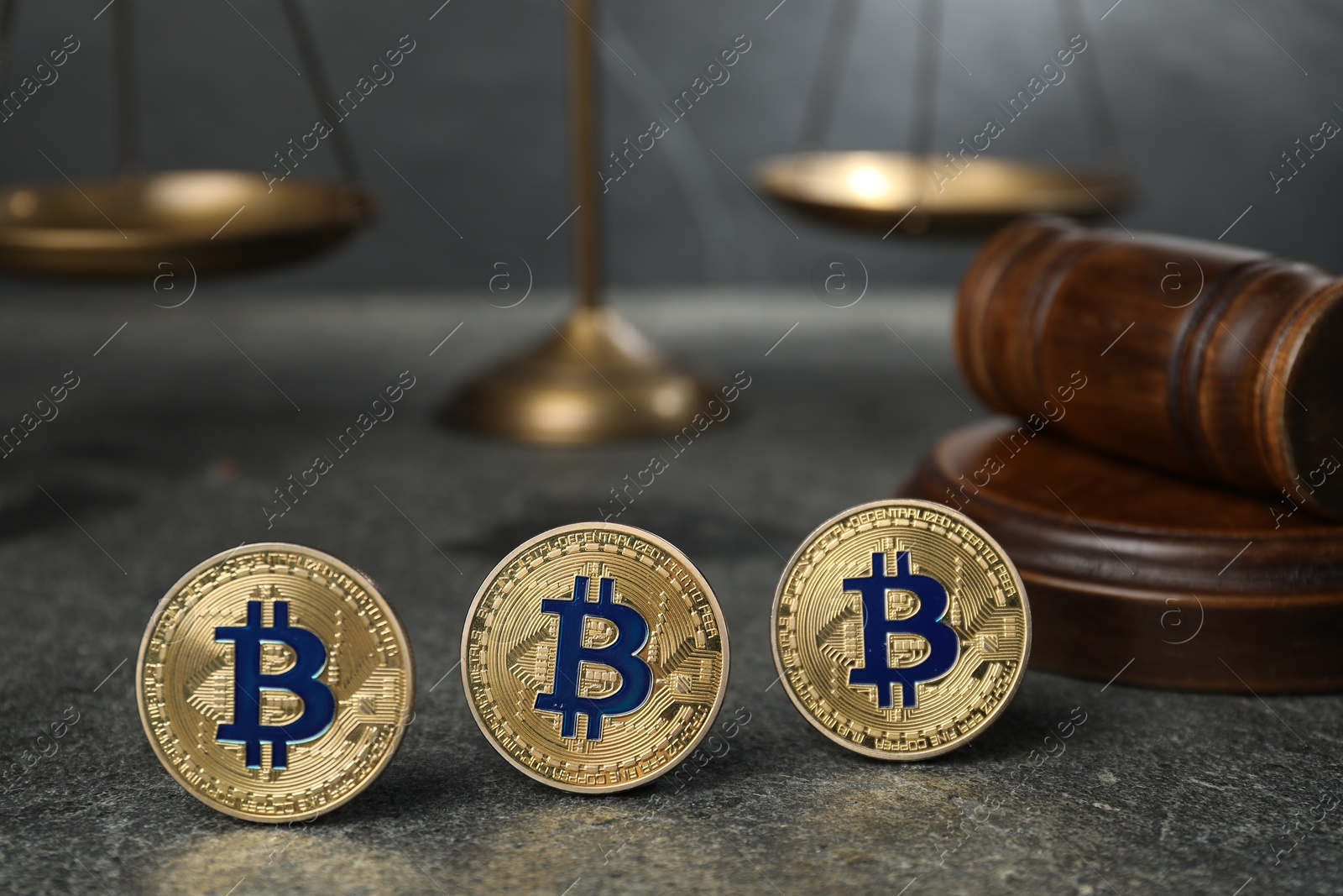 Photo of Cryptocurrency. Bitcoins, judge's gavel and scales on grey table, closeup