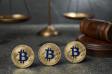 Photo of Cryptocurrency. Bitcoins, judge's gavel and scales on grey table, closeup
