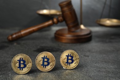Photo of Cryptocurrency. Bitcoins, judge's gavel and scales on grey table, closeup