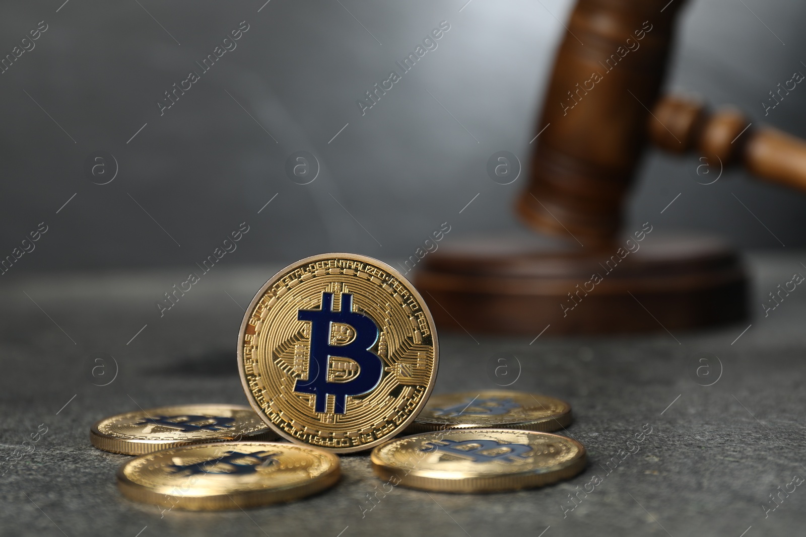 Photo of Cryptocurrency. Bitcoins and judge's gavel on grey table, closeup