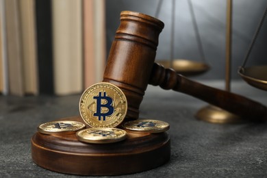 Photo of Cryptocurrency. Bitcoins, judge's gavel, books and scales on grey table, closeup