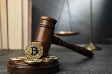 Photo of Cryptocurrency. Bitcoins, judge's gavel, books and scales on grey table, closeup