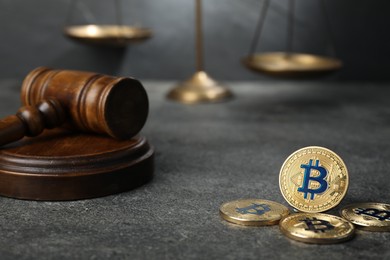 Photo of Cryptocurrency. Bitcoins, judge's gavel and scales on grey table, closeup