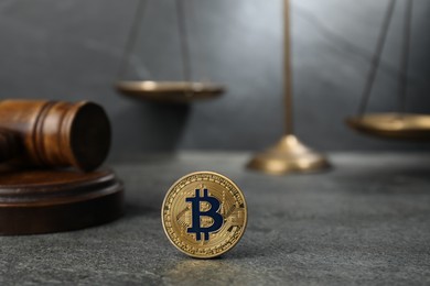 Photo of Cryptocurrency. Bitcoin, judge's gavel and scales on grey table, closeup