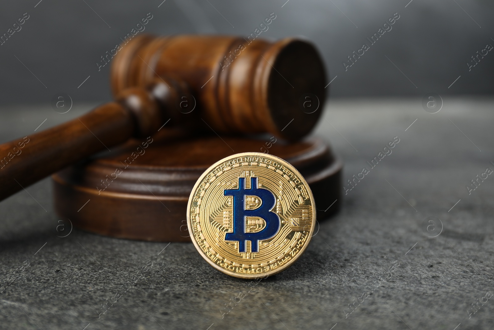 Photo of Cryptocurrency. Bitcoin and judge's gavel on grey table, closeup