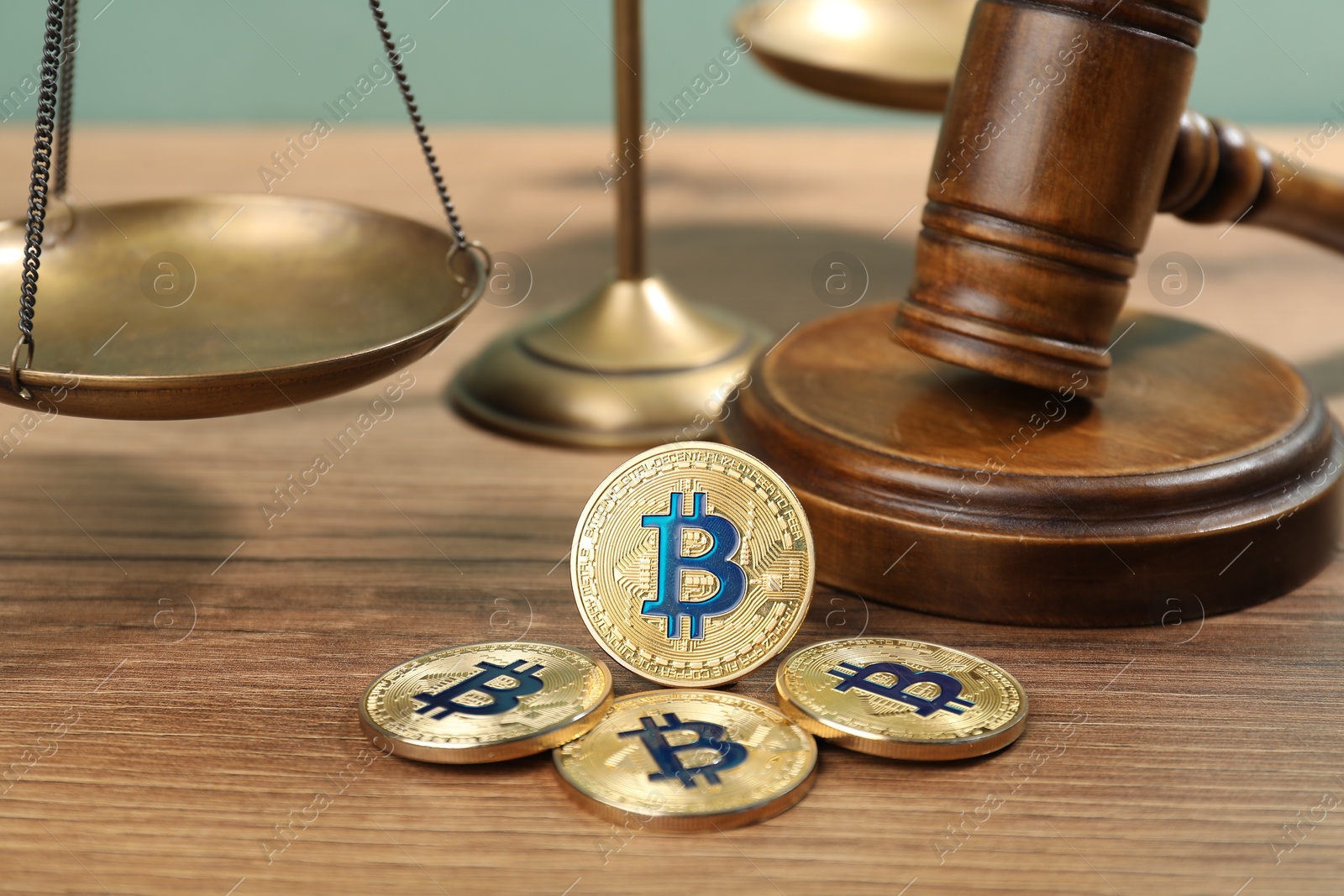 Cryptocurrency. Bitcoins, judge's gavel and scales on wooden table, closeup Photo of Cryptocurrency. Bitcoins, judge's gavel and scales on wooden table, closeup