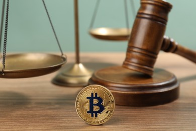 Photo of Cryptocurrency. Bitcoin, judge's gavel and scales on wooden table, closeup