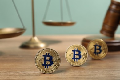 Photo of Cryptocurrency. Bitcoins, judge's gavel and scales on wooden table, closeup