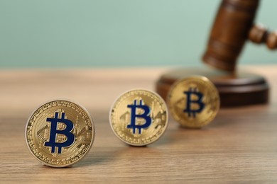 Photo of Cryptocurrency. Bitcoins and judge's gavel on wooden table, closeup